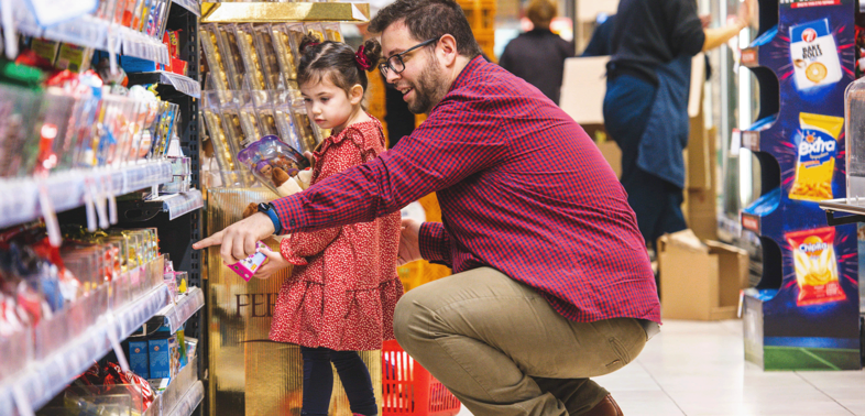 Father and daughter pointing to the candies in the supermarket from Alfa Beta