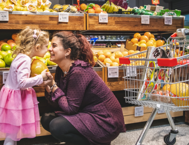 Mother and daughter smiling to each other in front of apples in supermarket Mega Image